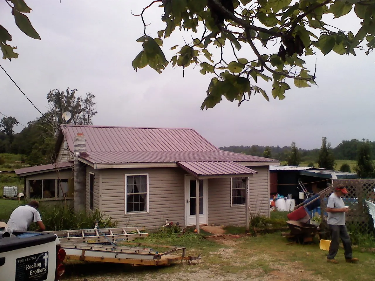Crew finishing a mauve metal roof on a small farmhouse in Arvilla