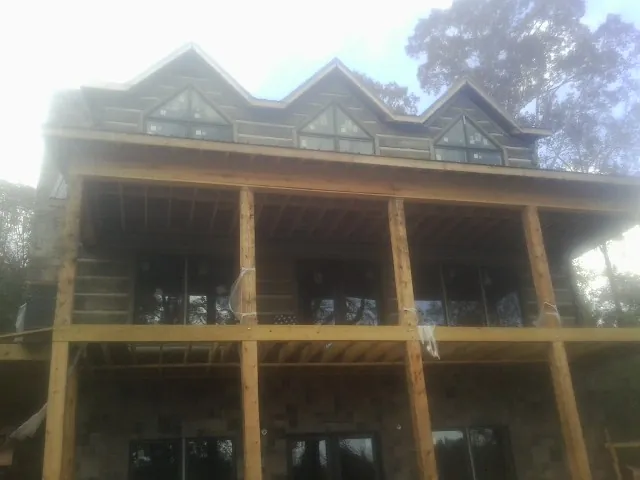 Dormers and porch framing on a large log home under construction — Roof Coating work by our crew in Arvilla
