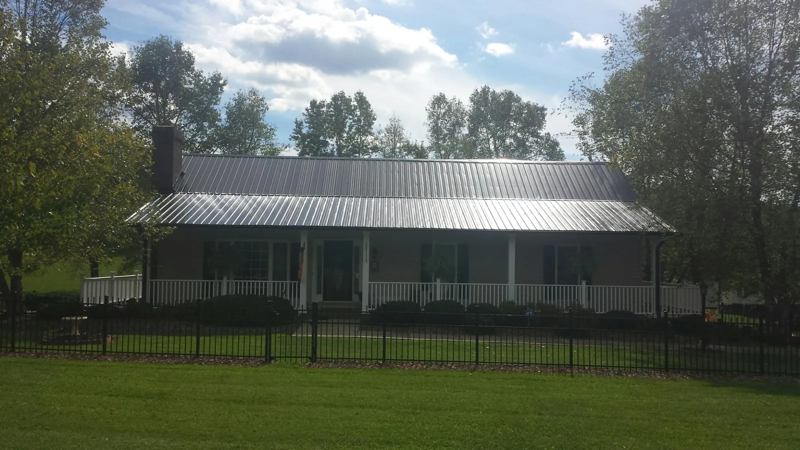 Gray metal roof on a brick ranch with a full width front porch — Gutter Guard Installation work by our crew in Arvilla