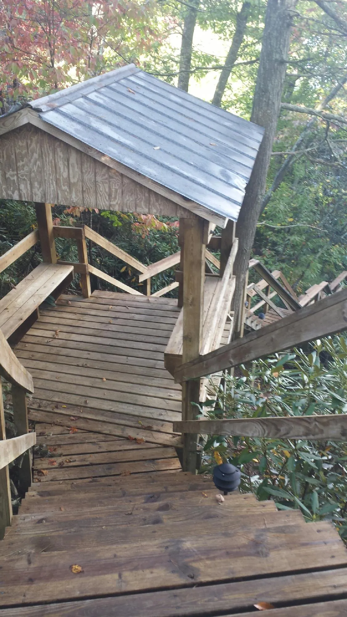 Metal roofed shelter over wooden steps on a wooded walkway — Skylight Repair & Installation work by our crew in Arvilla