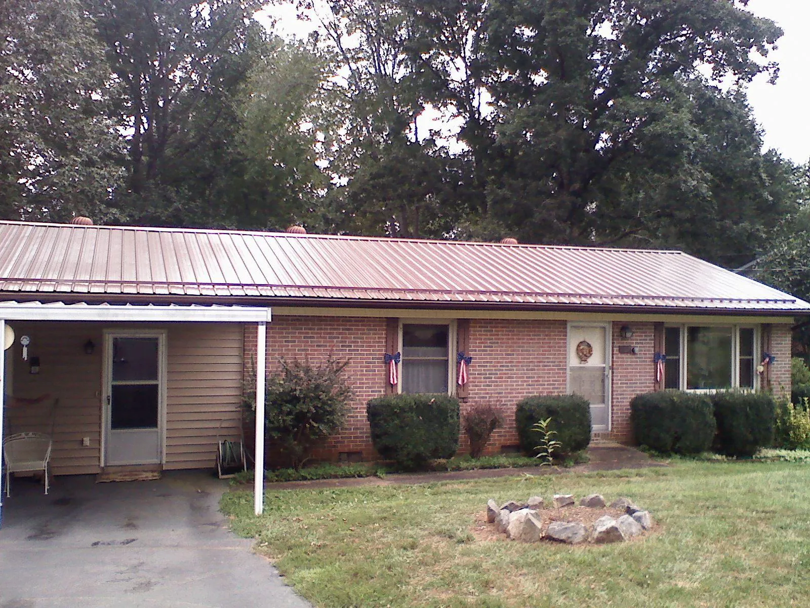 Bronze metal roof and carport on a brick ranch home — Roof Repair work by our crew in Arvilla