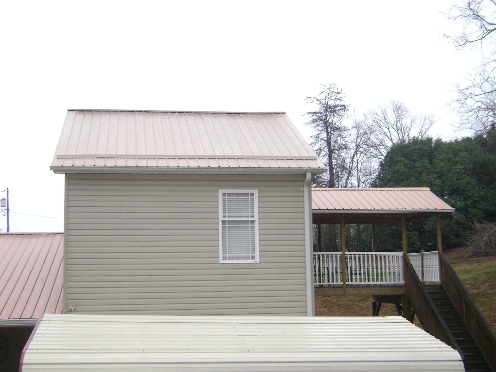 Tan metal roofs on a two story addition and attached porch, from a Roof Replacement job in Arvilla