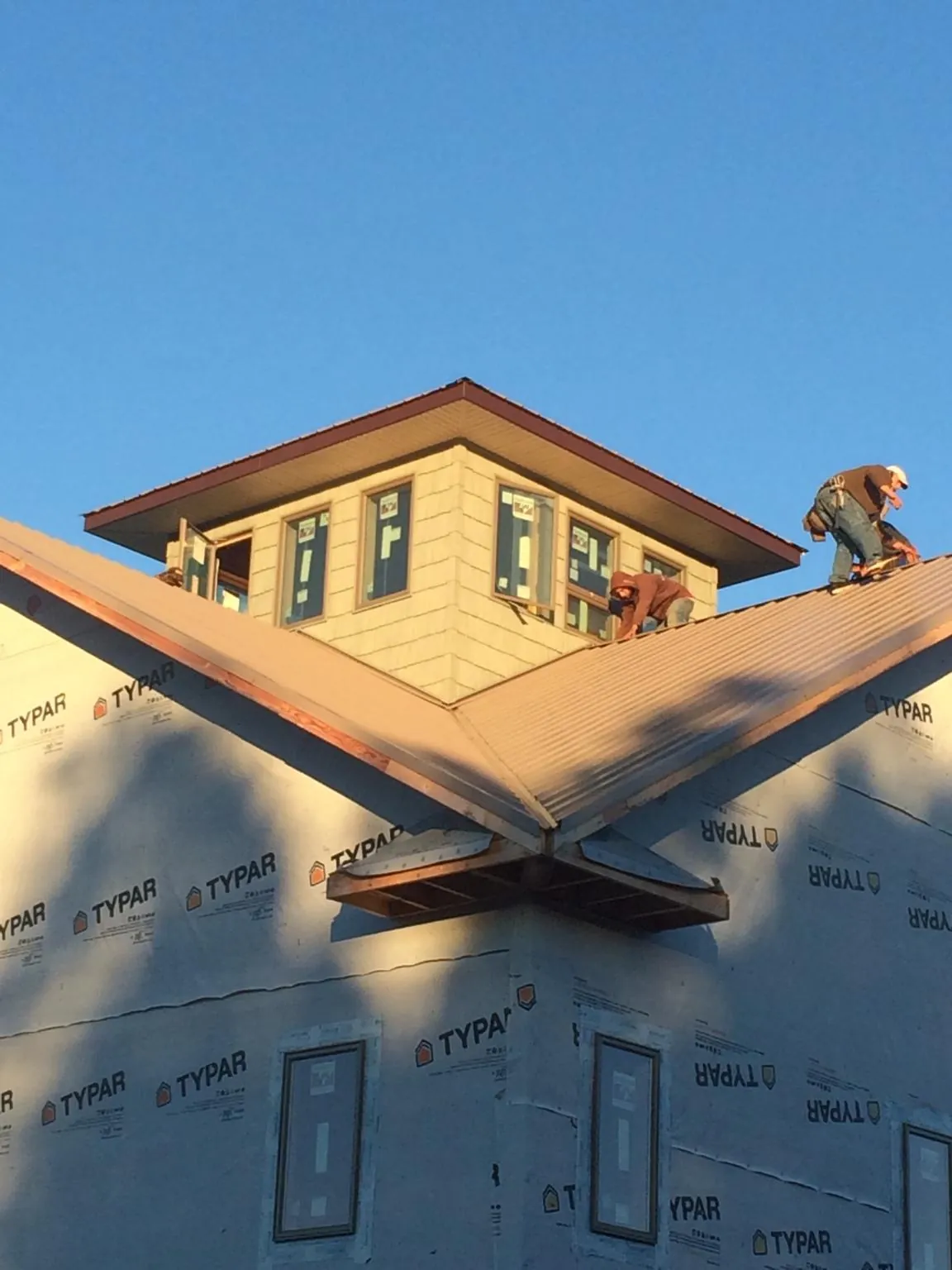 Roofers working around a rooftop cupola on a new metal roof at sunset — Roof Waterproofing in Arvilla by Roofing Brothers